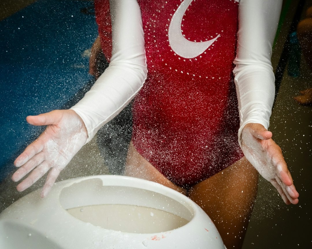 Gymnast claps hands together to release chalk dust over a bucket.